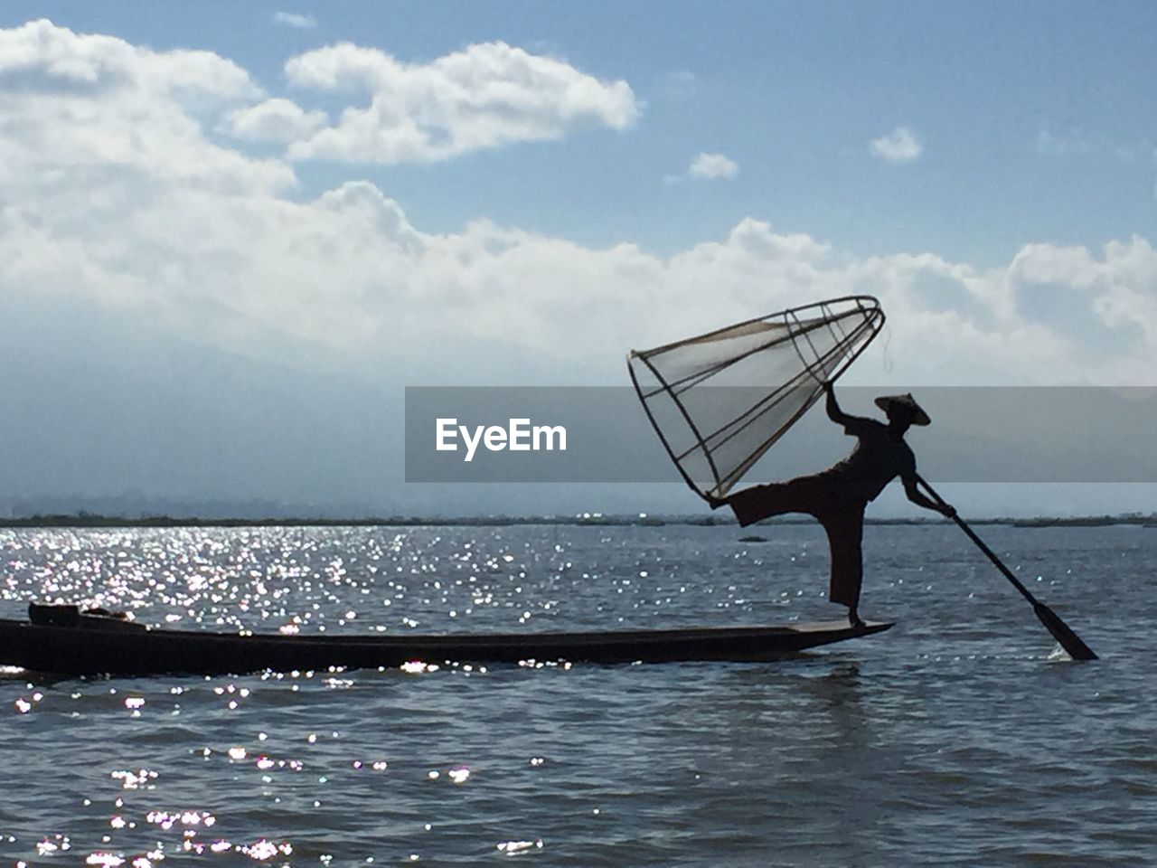 Silhouette man fishing in sea against sky 