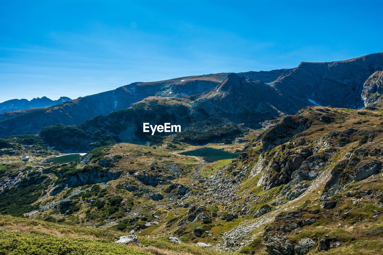 Scenic view of mountains against blue sky