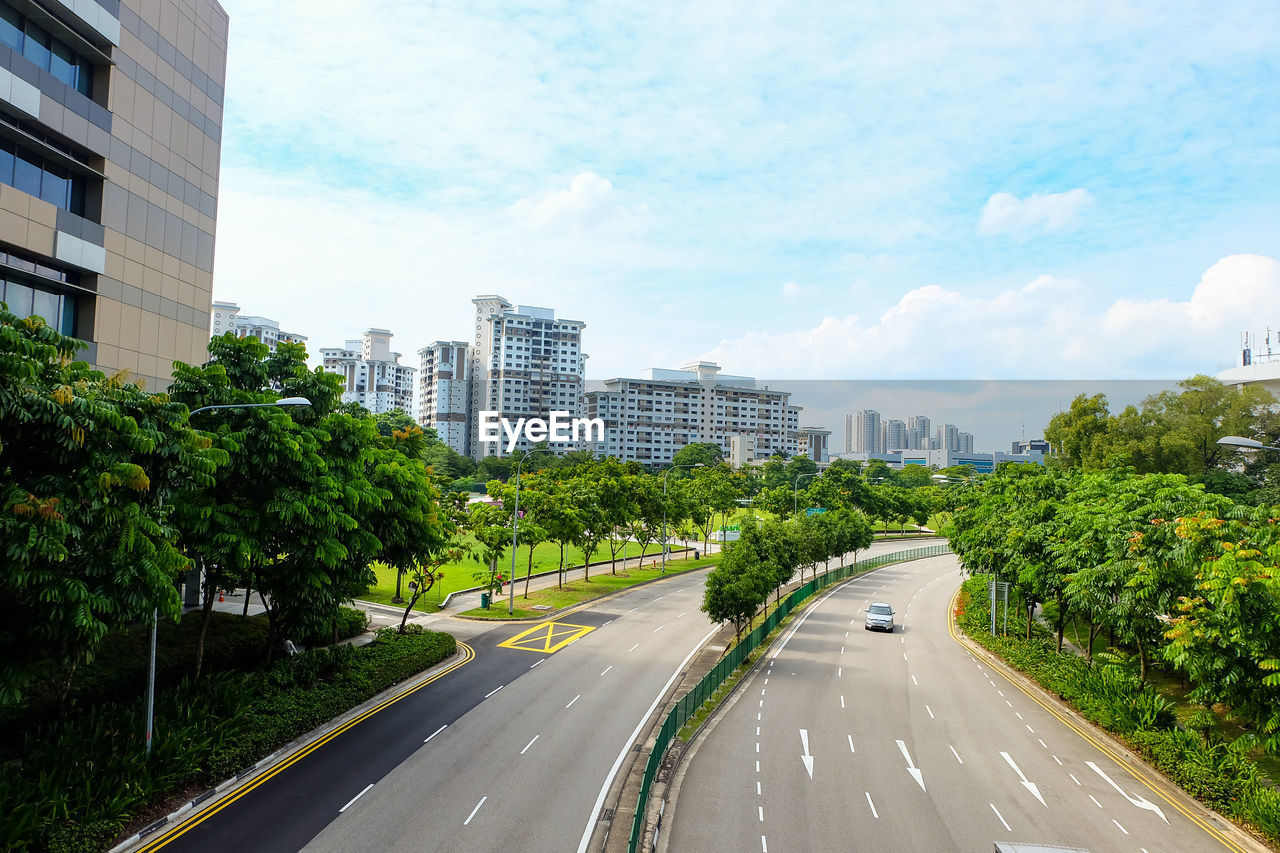 Road by buildings in city against sky