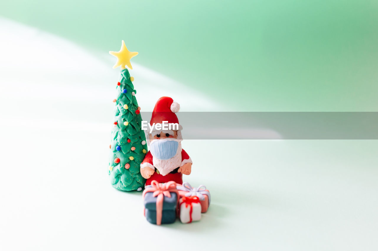 Clay christmas concept. colorful handmade miniature christmas tree and santa claus with mask. 2021