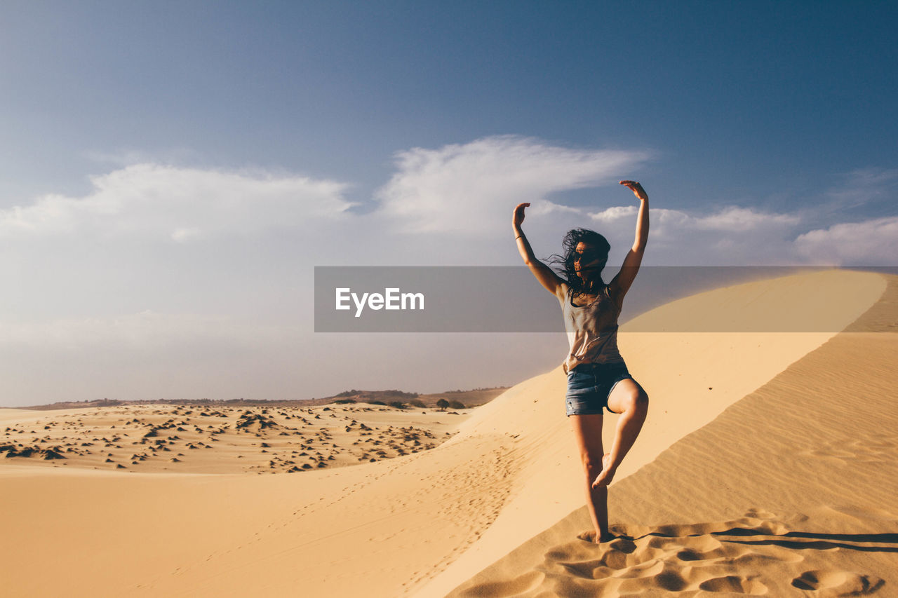 Woman standing on sand at beach against sky