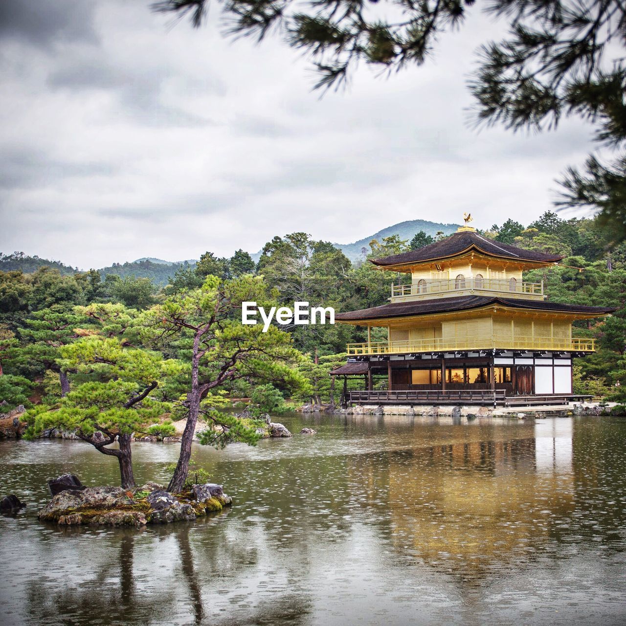 Kinkaku-ji near lake against cloudy sky