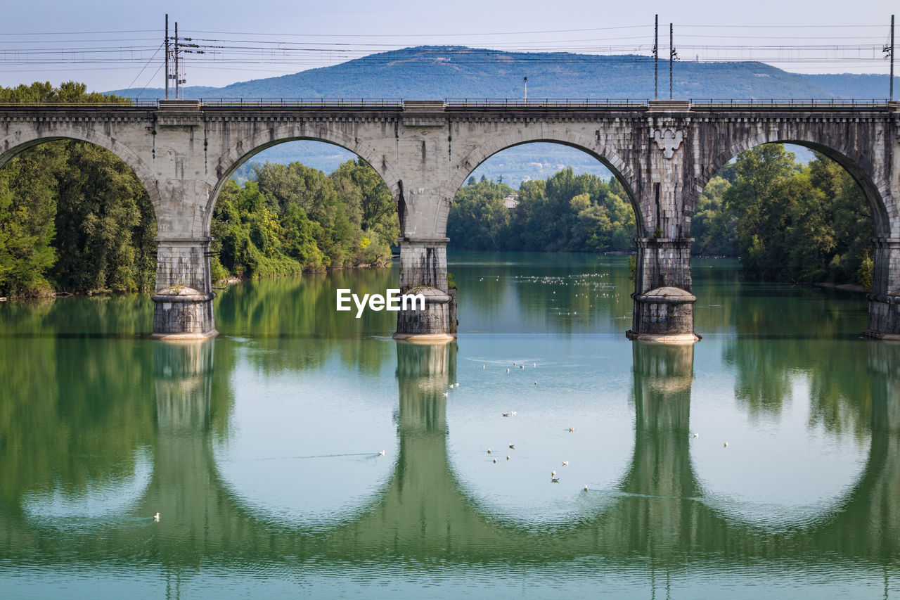 Arch bridge over river against sky