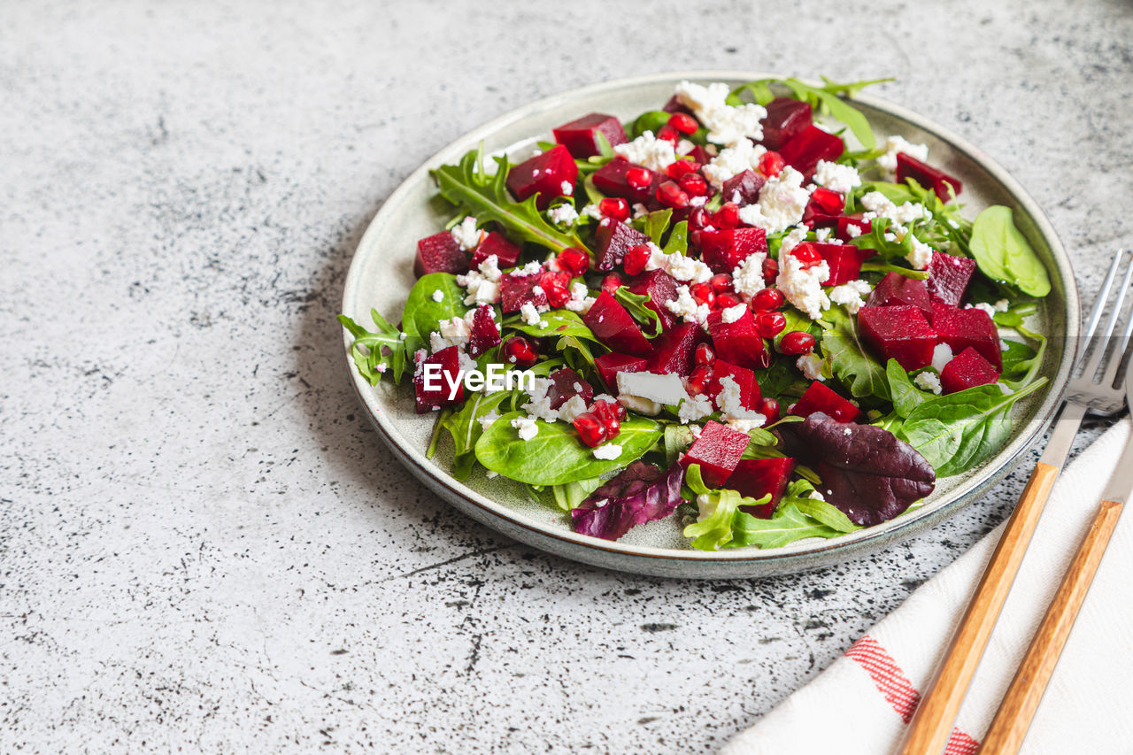 Arugula, beet and cheese salad with pomegranate and dressing on plate