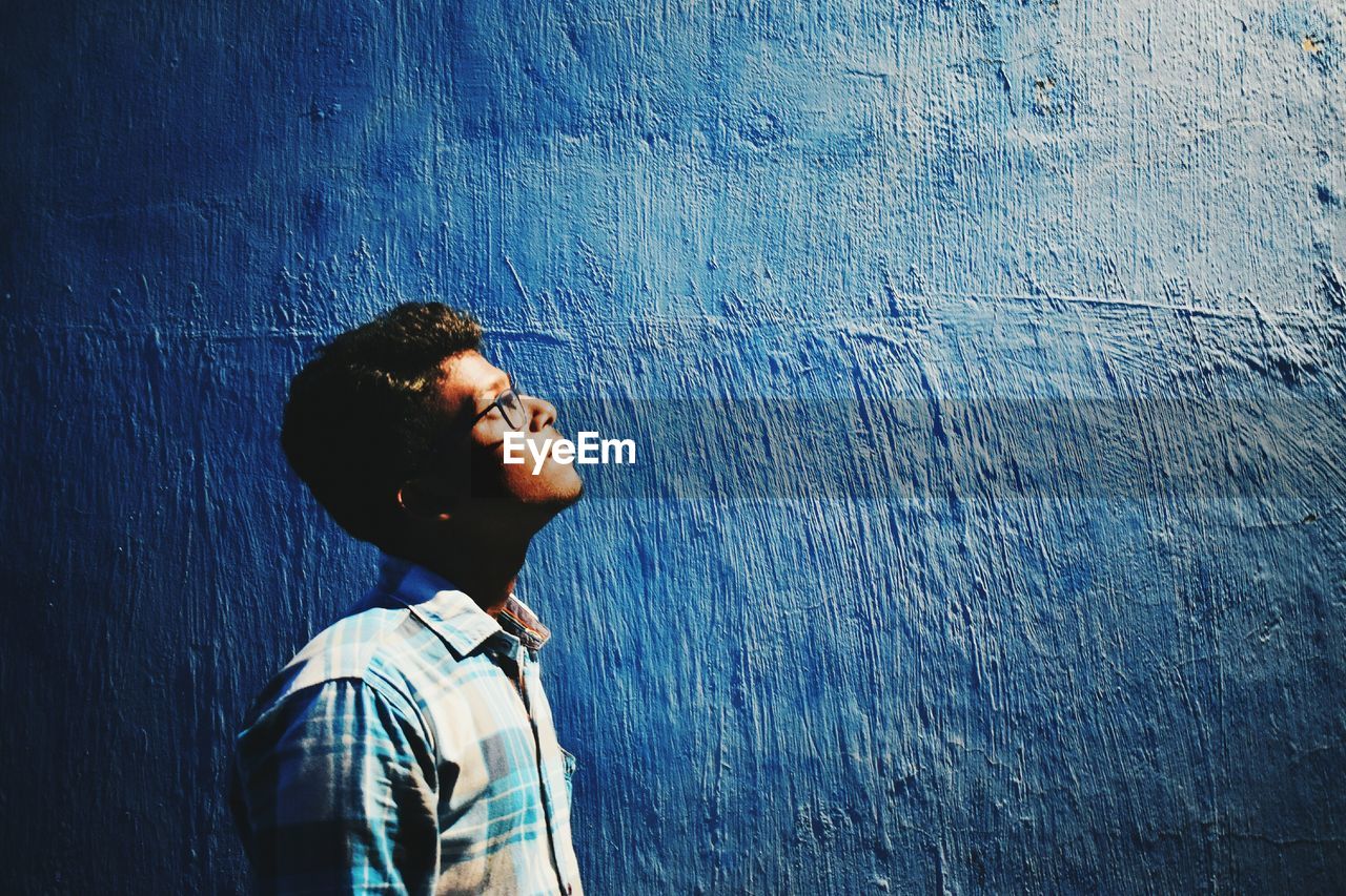 Close-up of man against blue wall