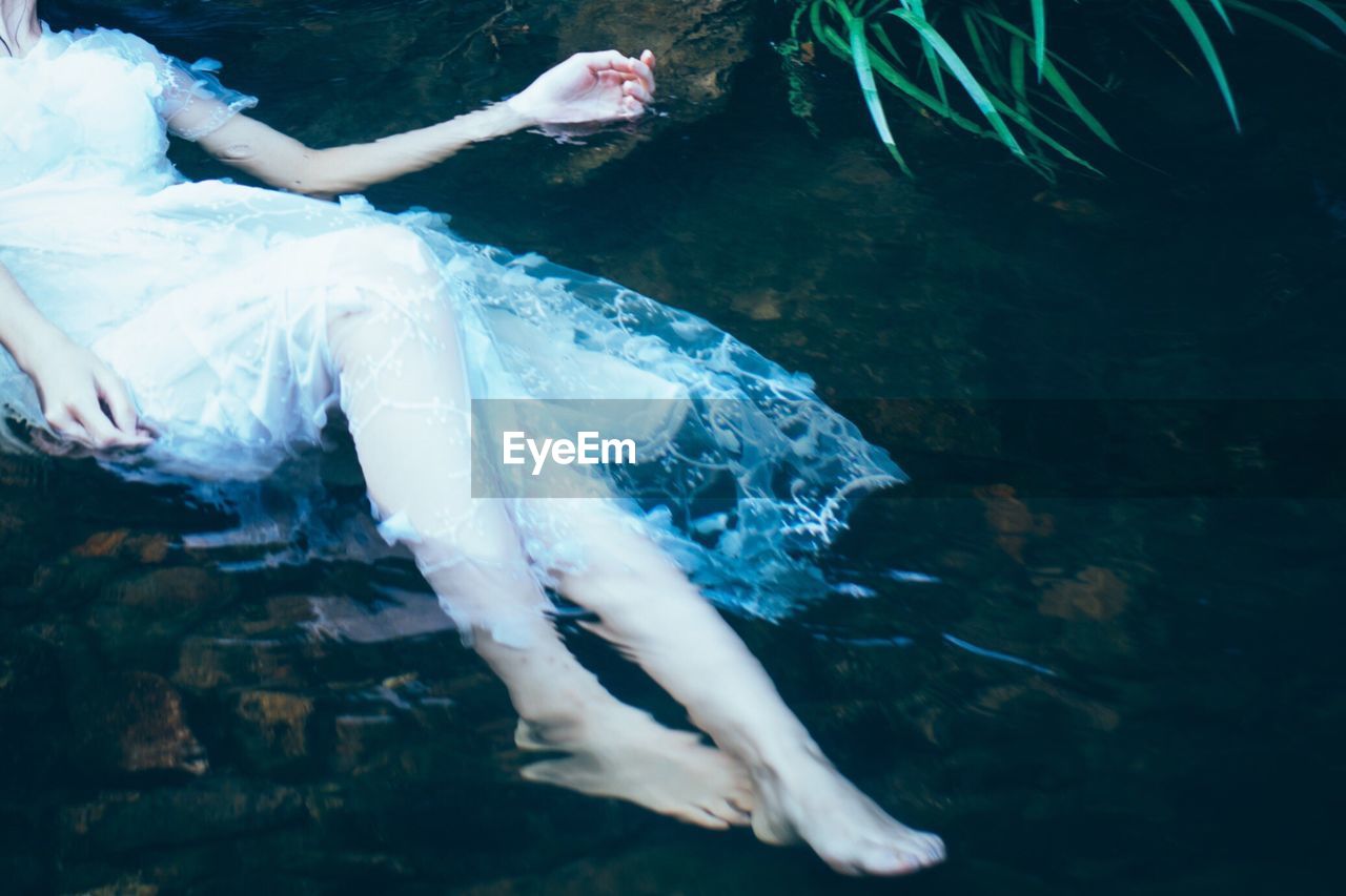 Low section of woman relaxing in water