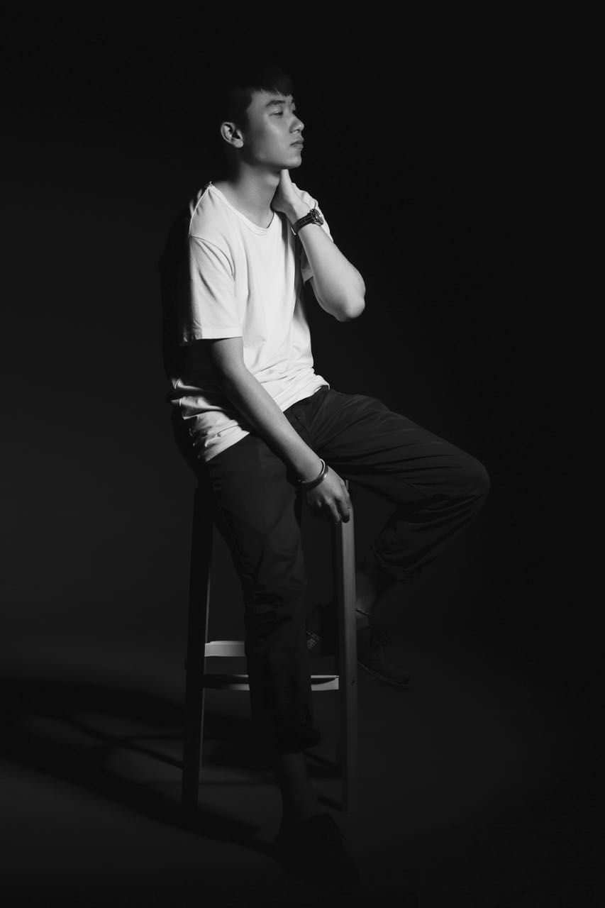Thoughtful man sitting on stool against black background