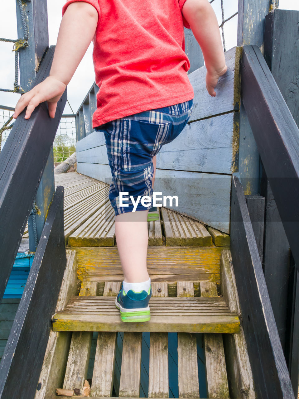 Low section of boy moving on wooden steps at park