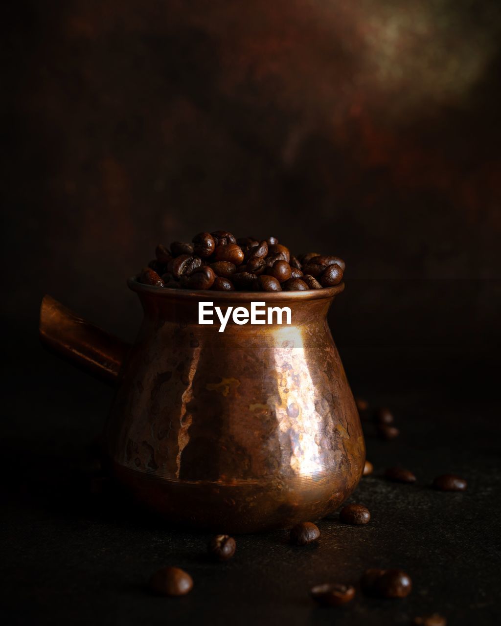 Coffee beans in copper java on dark brown background 