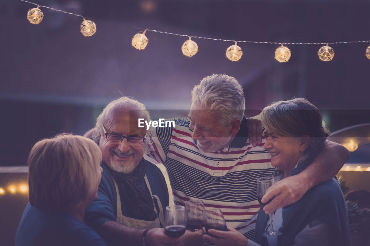 Happy senior couples toasting wine at night