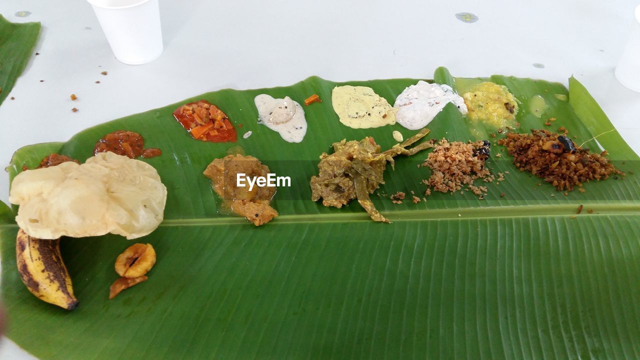 High angle view of indian food served on banana leaf on floor