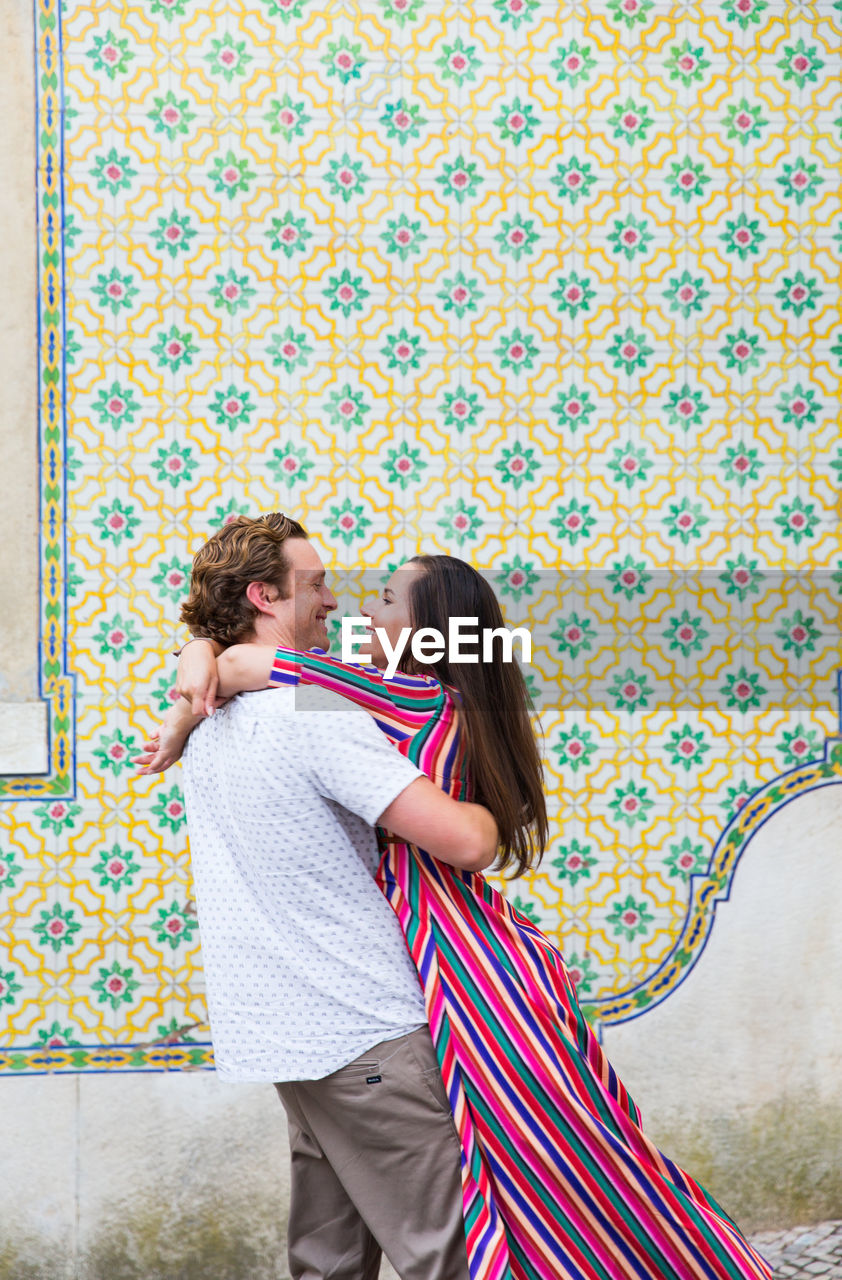 Man and woman embracing against wall