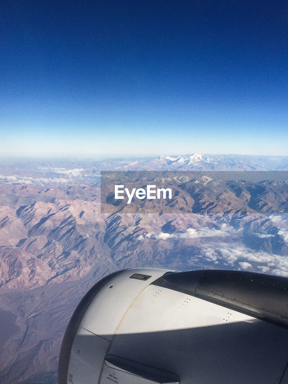 AERIAL VIEW OF AIRCRAFT WING OVER LANDSCAPE AGAINST CLEAR SKY