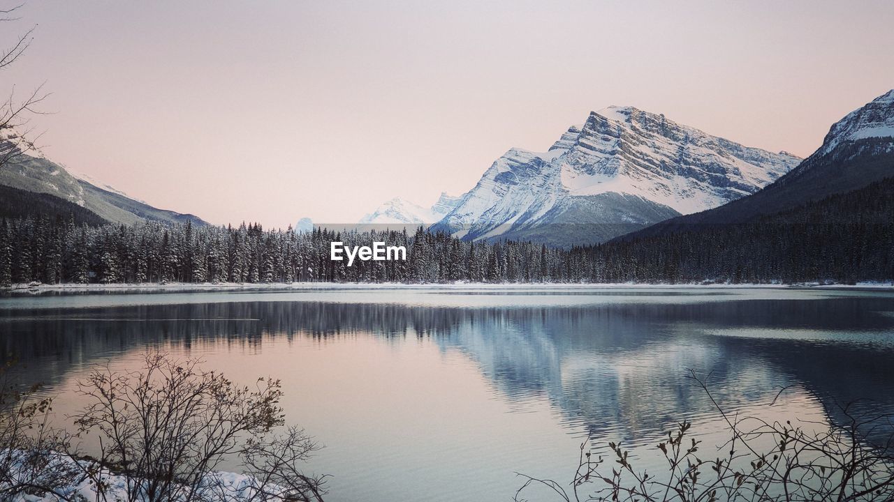 Scenic view of lake by snowcapped mountains against sky