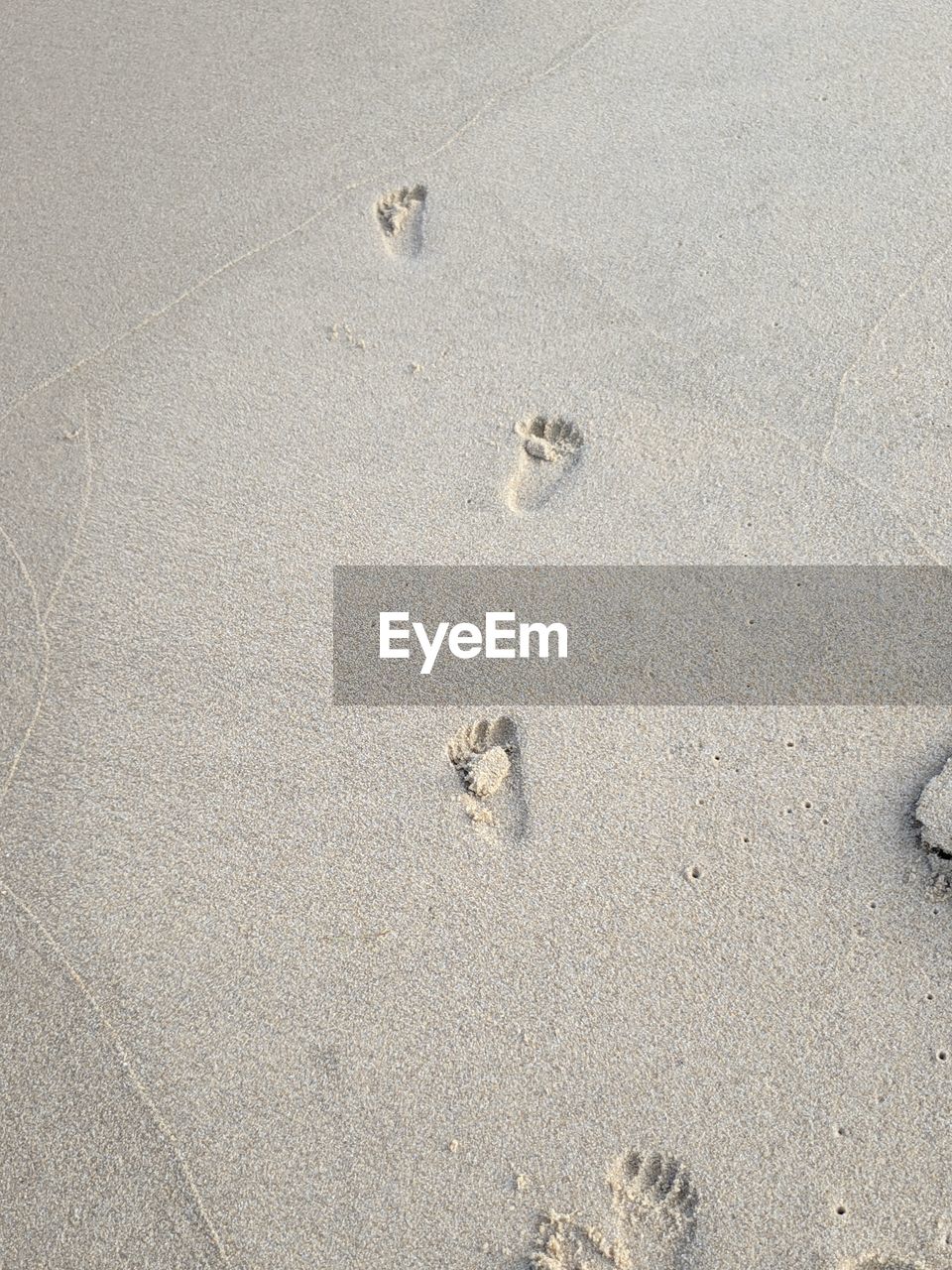 HIGH ANGLE VIEW OF FOOTPRINTS ON BEACH