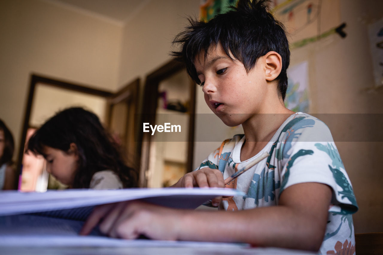 Sitting at kitchen table children doing homework at home