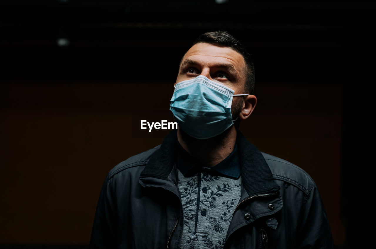 Portrait of man wearing a mask on dark black background