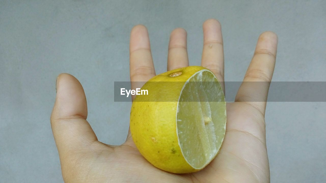 CLOSE-UP OF HAND HOLDING LEMON