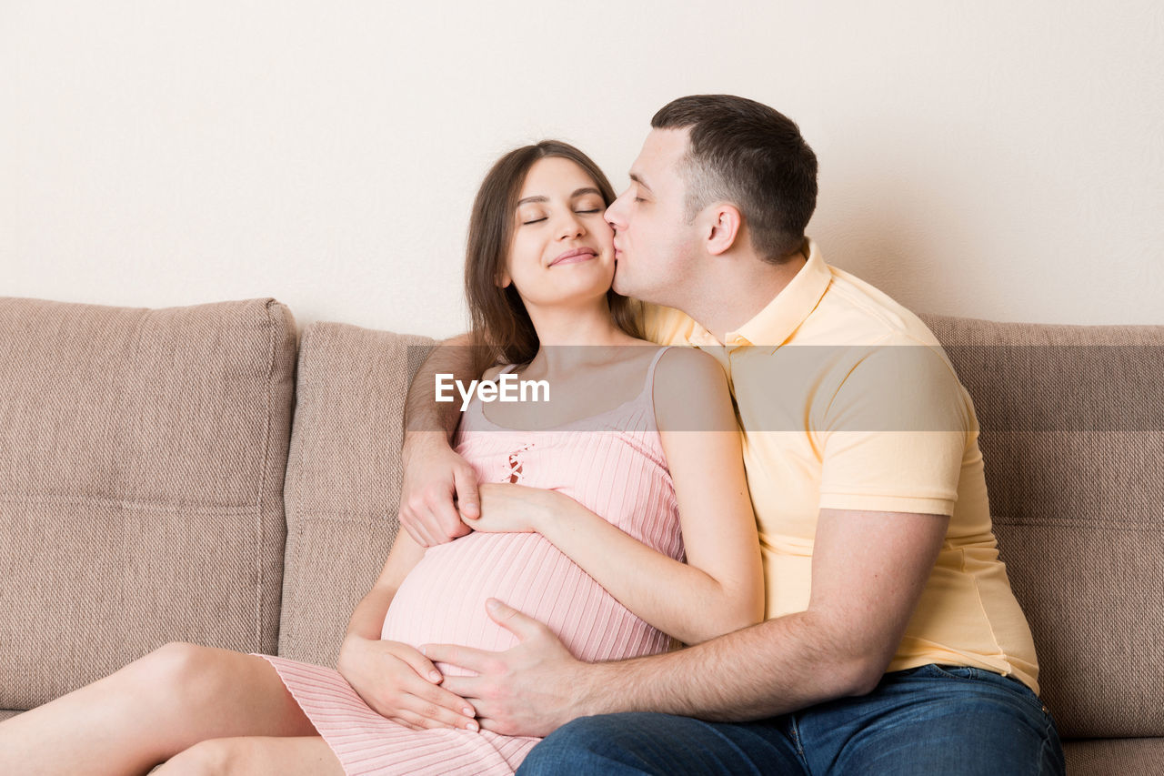 Happy pregnant woman and her husband waiting for baby at the home. happy family love and care.