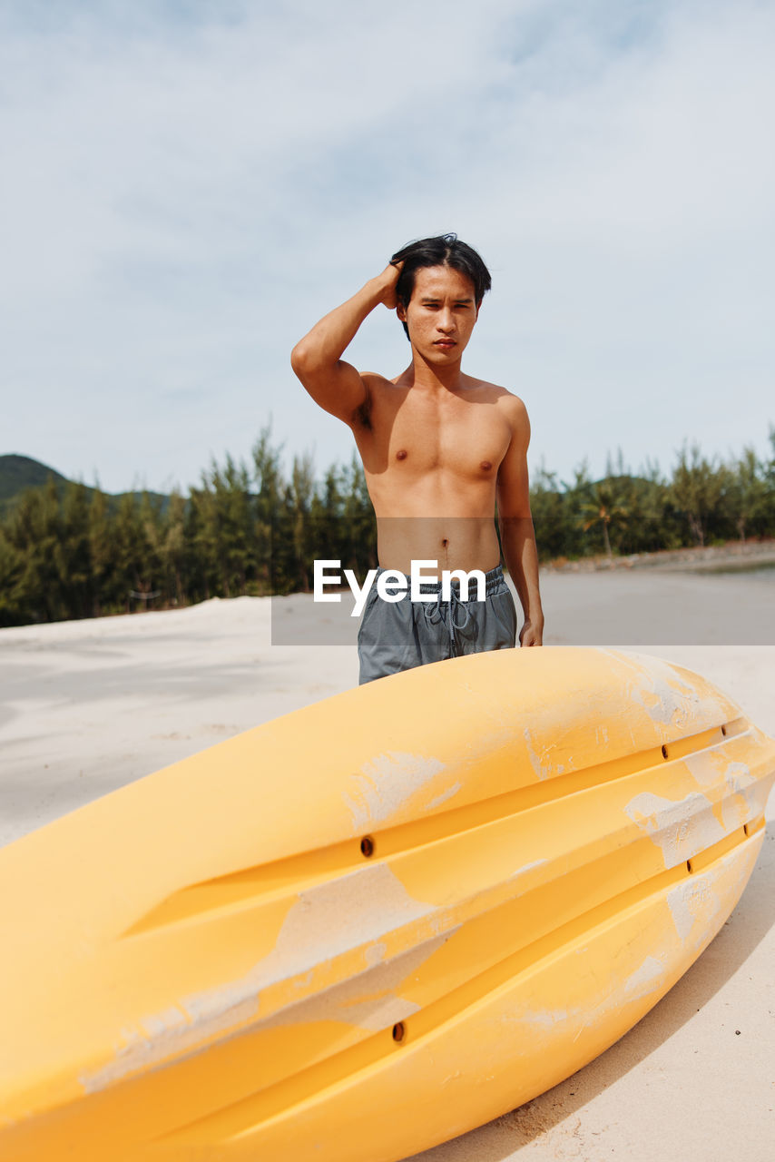 rear view of shirtless man sitting on boat on sea against sky