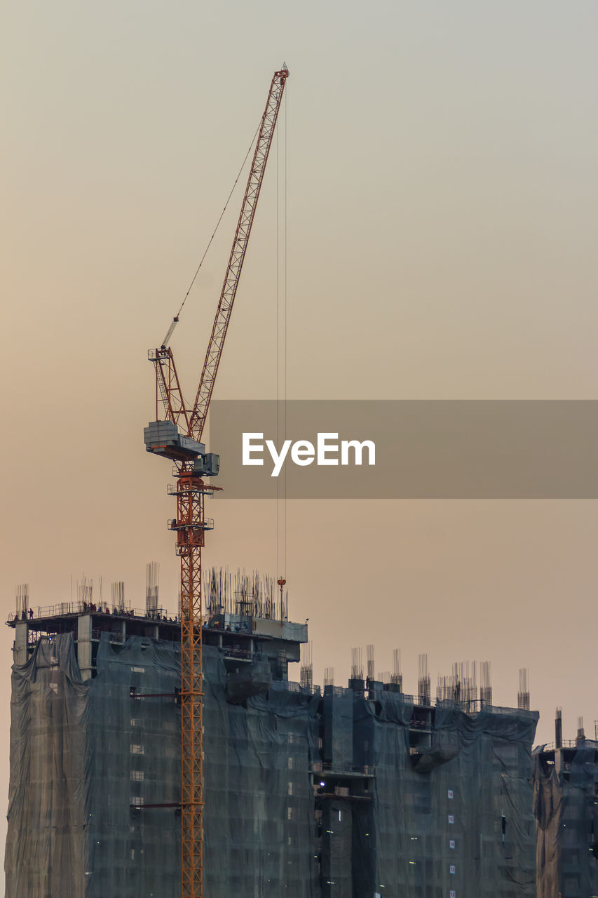 CRANES AT CONSTRUCTION SITE IN CITY AGAINST SKY