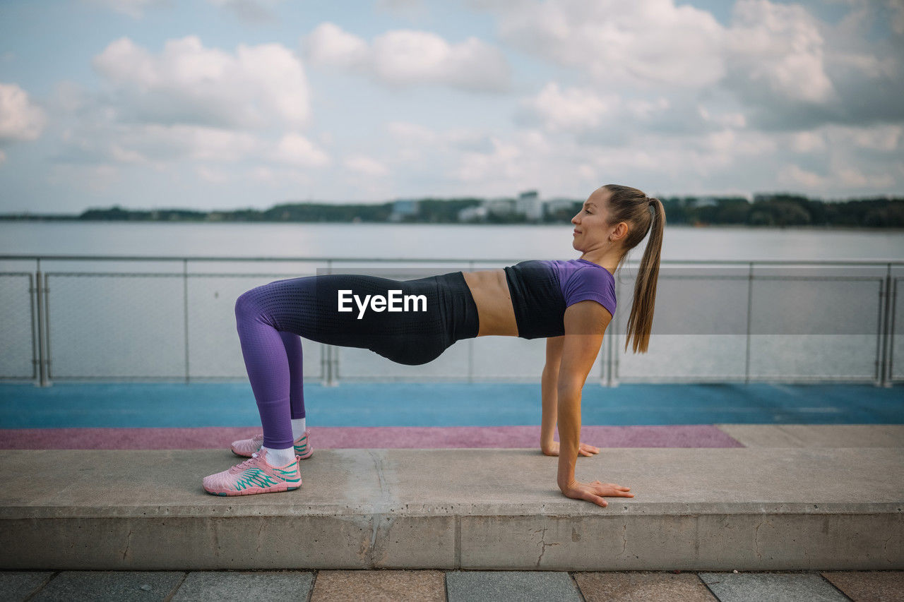 full length of young woman exercising on footpath