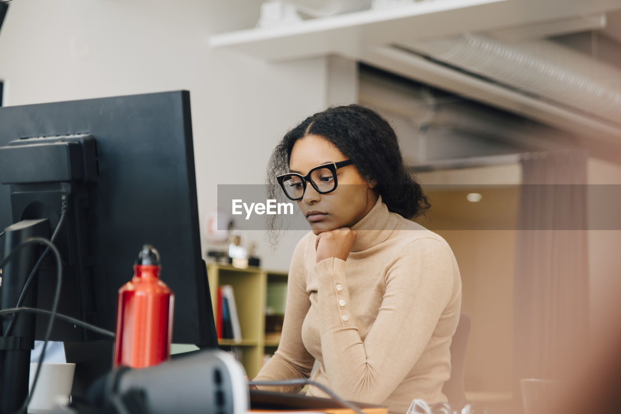 Focused female computer programmer working on laptop at desk in office