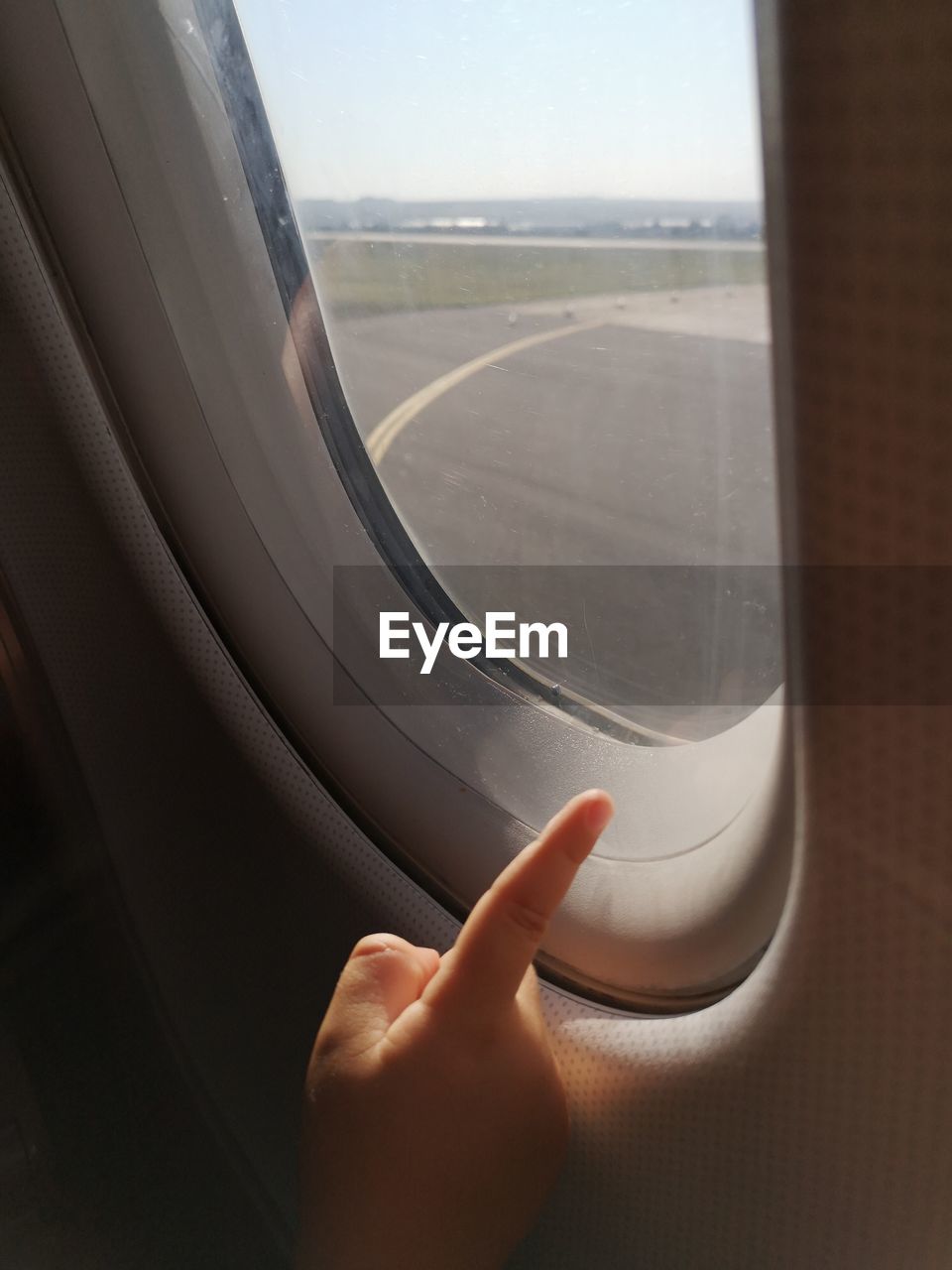 Cropped image of hand pointing by window in airplane