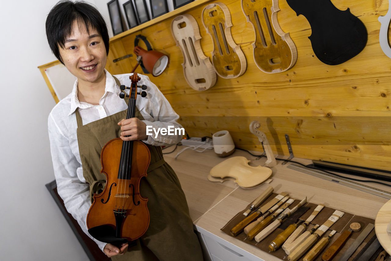 Young chinese violin maker at work in her workshop