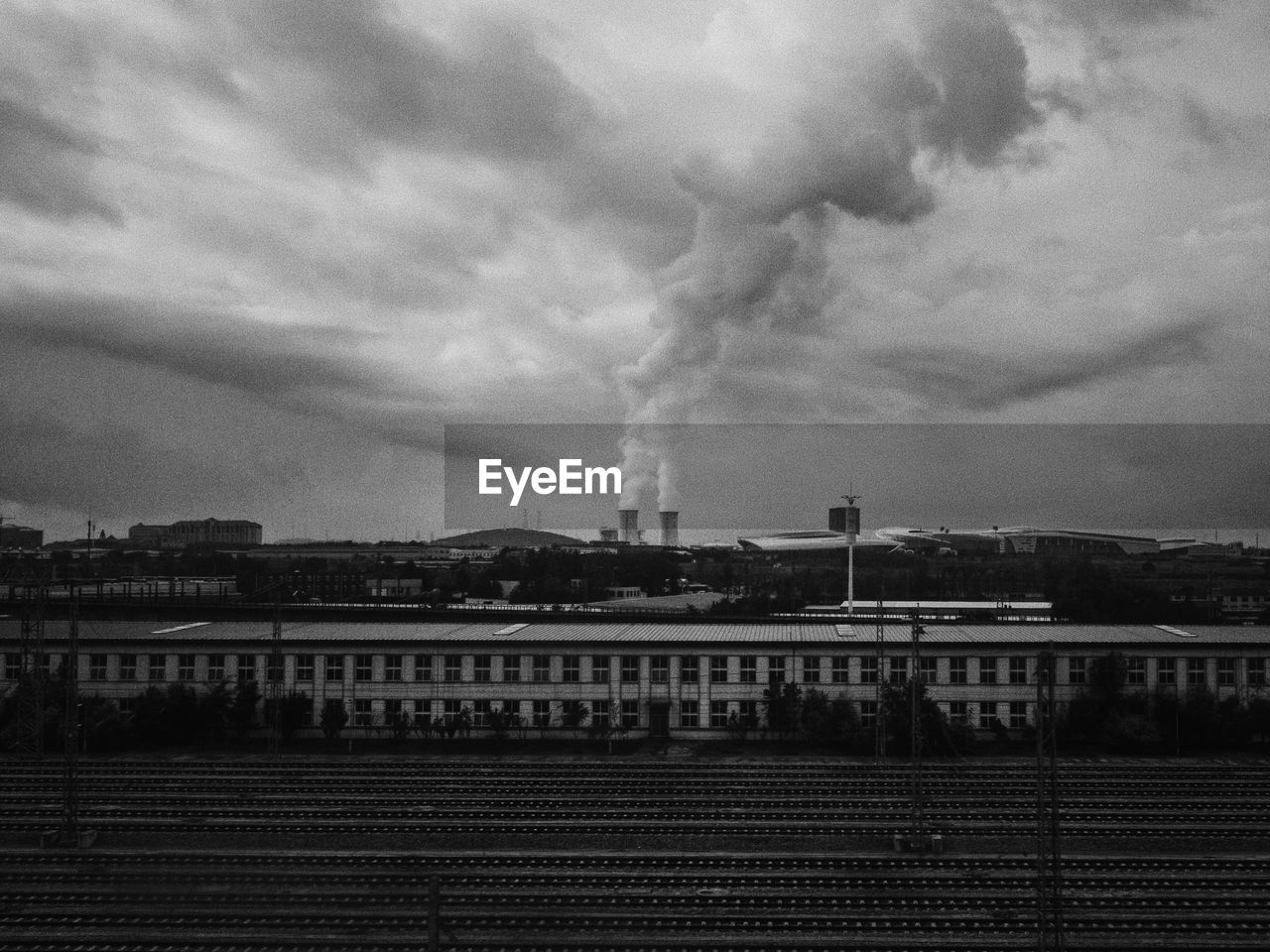 Smoke emitting chimneys against cloudy sky