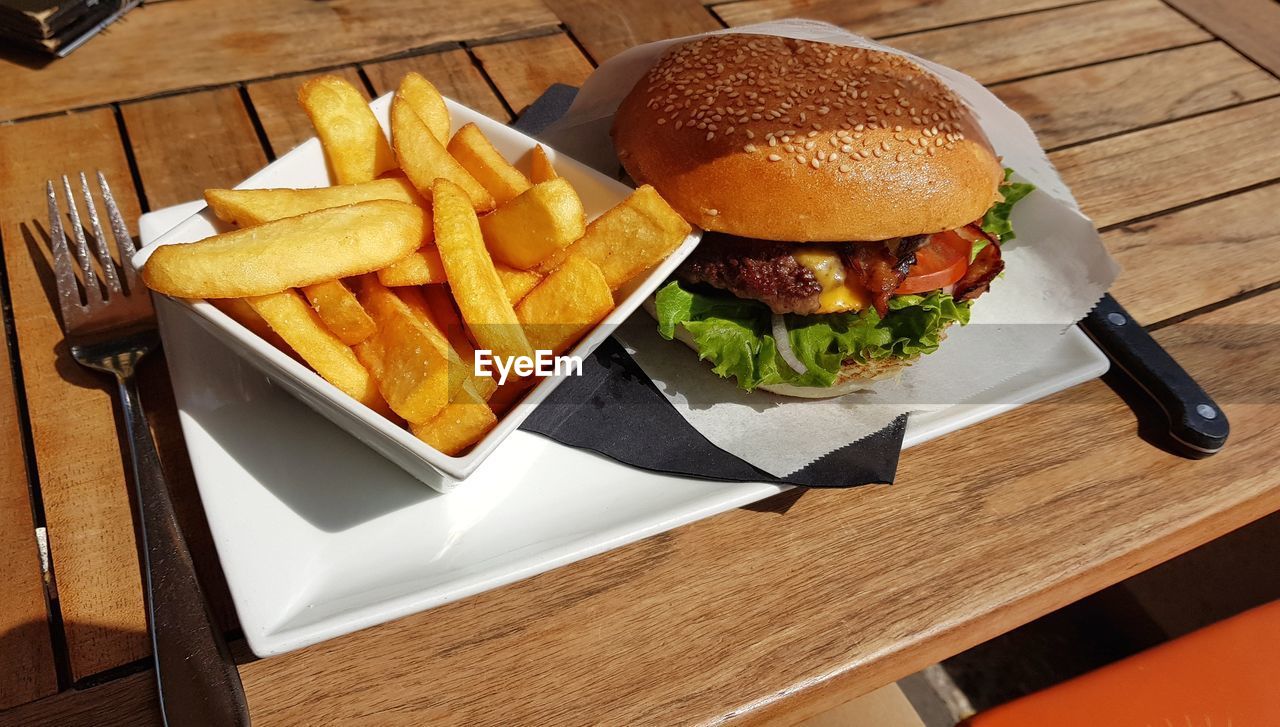 Close-up photo of burger and fries on table outdoor in restaurant