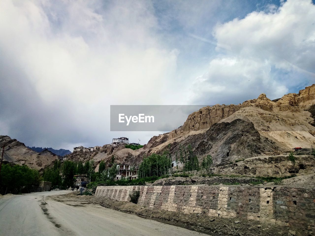 ROAD AMIDST MOUNTAINS AGAINST SKY