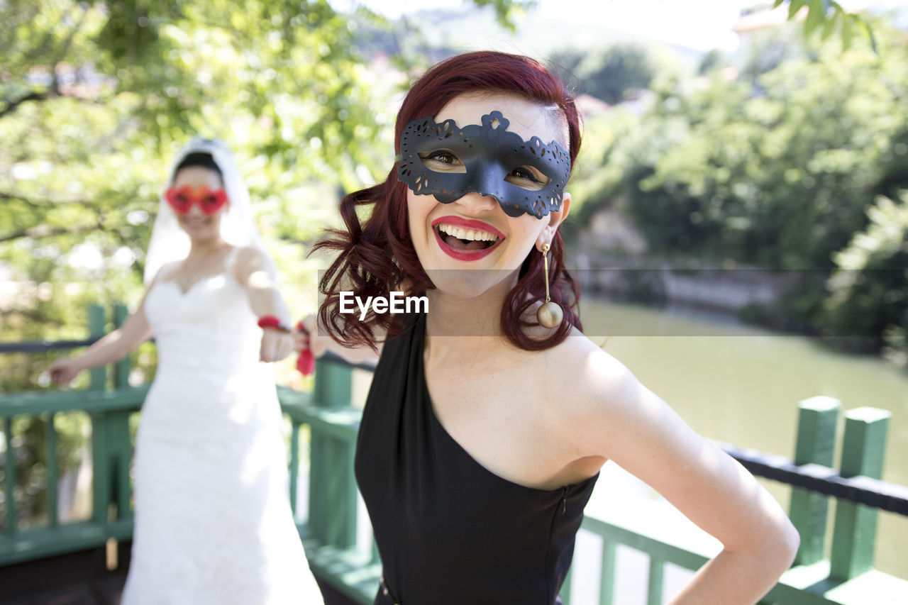 Portrait of woman pulling bride while standing against lake