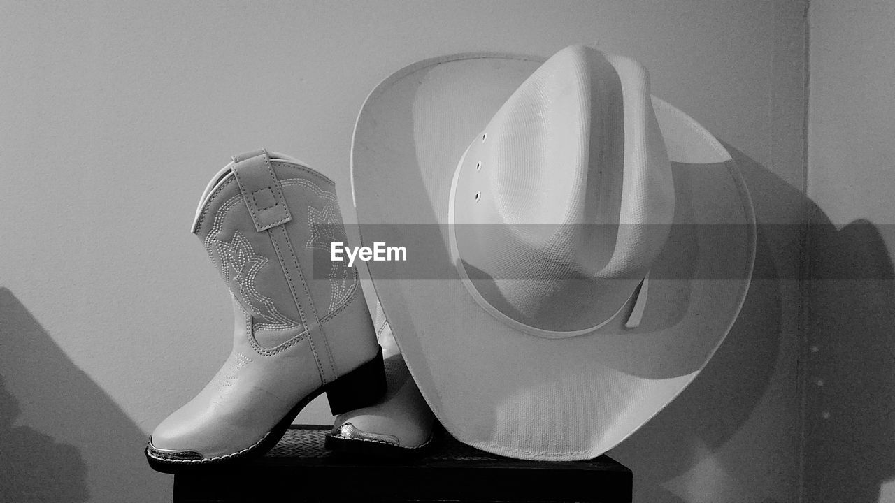 Cowboy boot and hat on table against wall at home