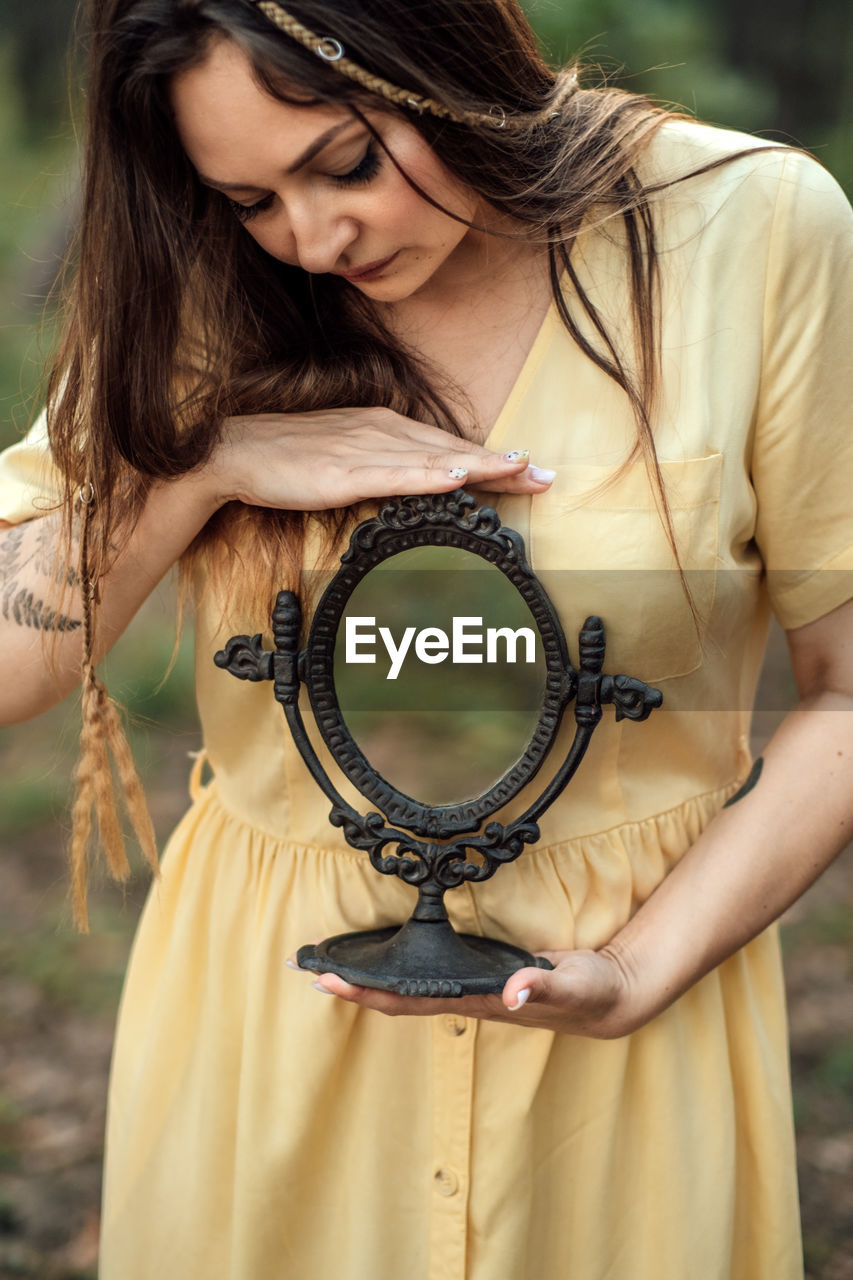 Woman with mirror instead of face on the forest background. mindfulness, mind and soul, mental