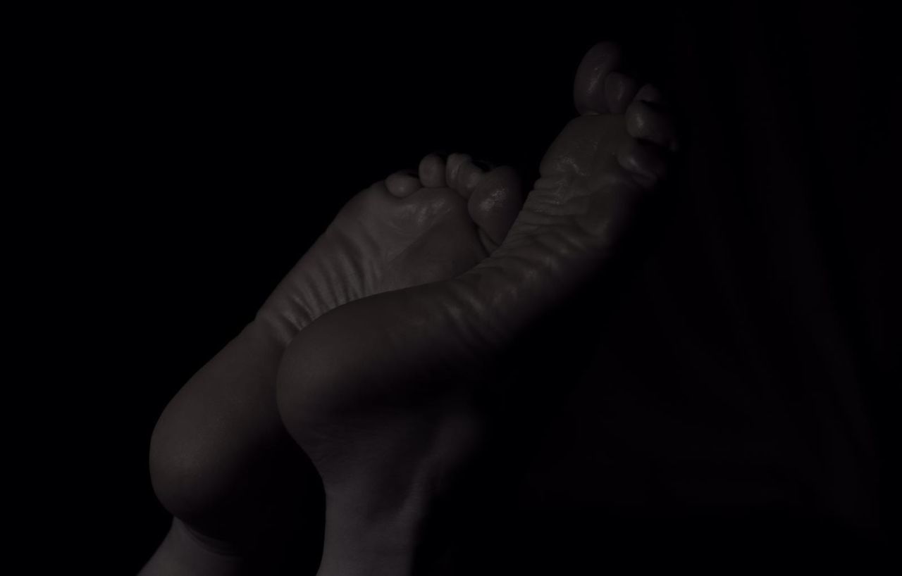 CLOSE-UP OF HANDS AGAINST BLACK BACKGROUND