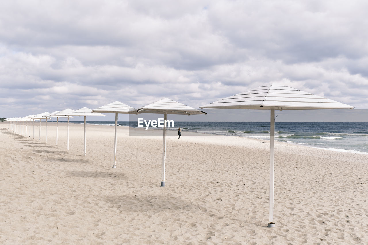 BEACH UMBRELLAS BY SEA AGAINST SKY