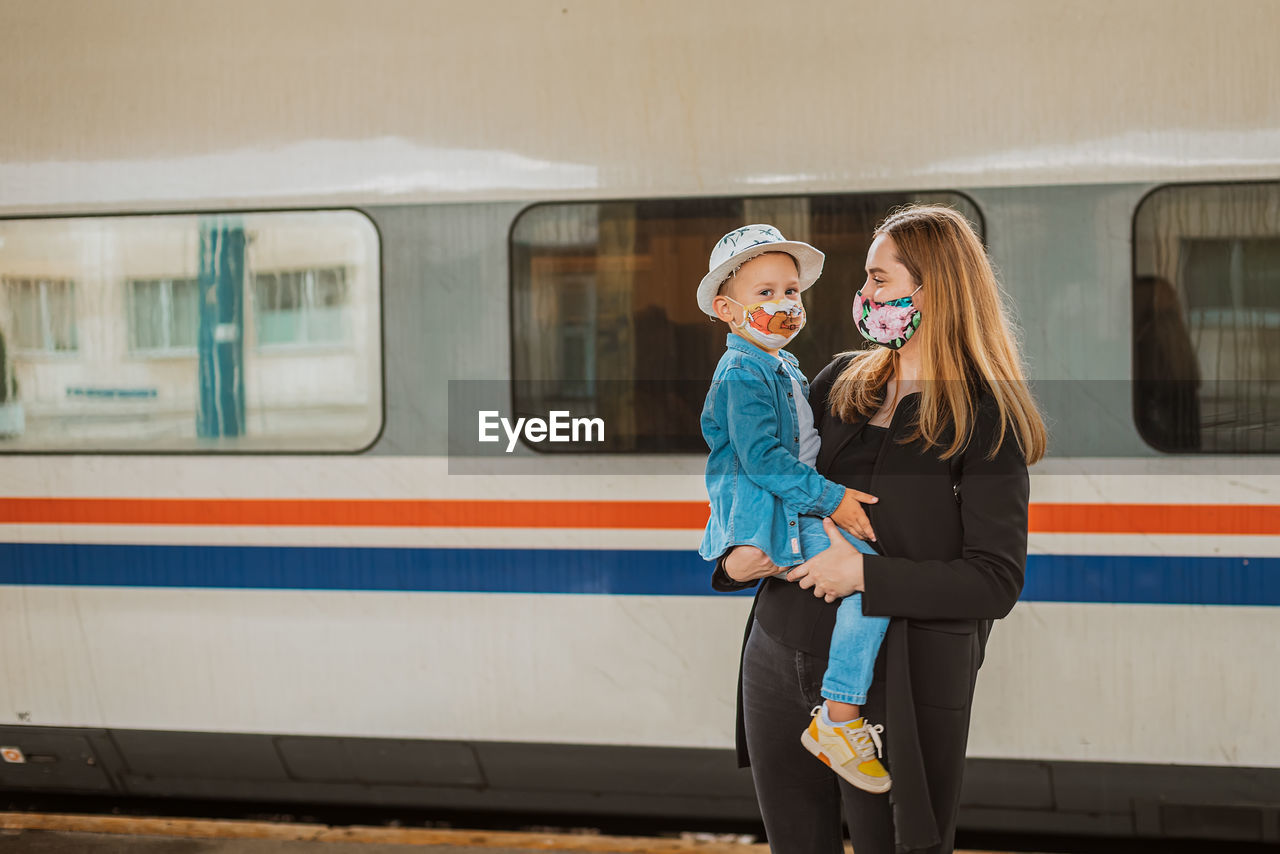 Mother looking while holding son at railroad station against train