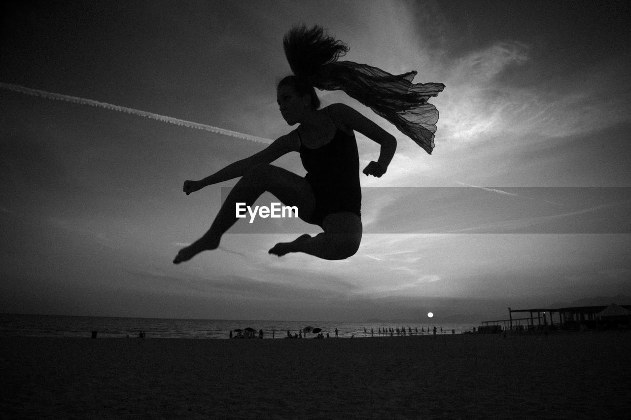 People jumping on beach against sky