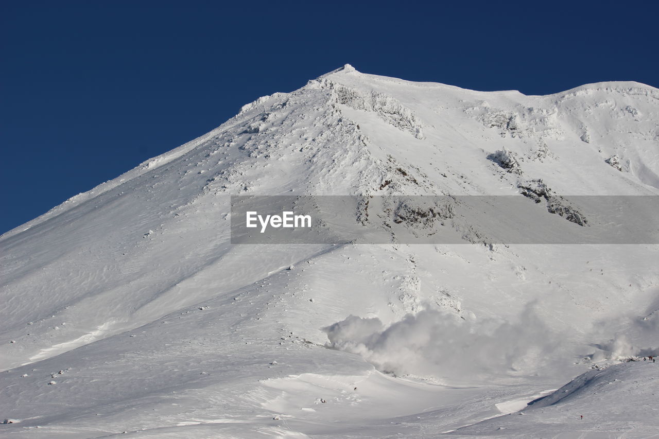 Scenic view of snowcapped mountains against clear blue sky