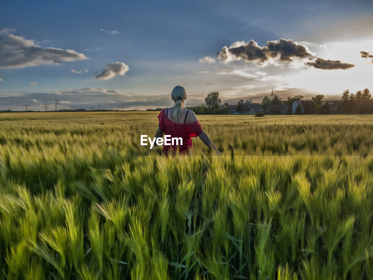 Rear view of woman walking on agricultural field against sky