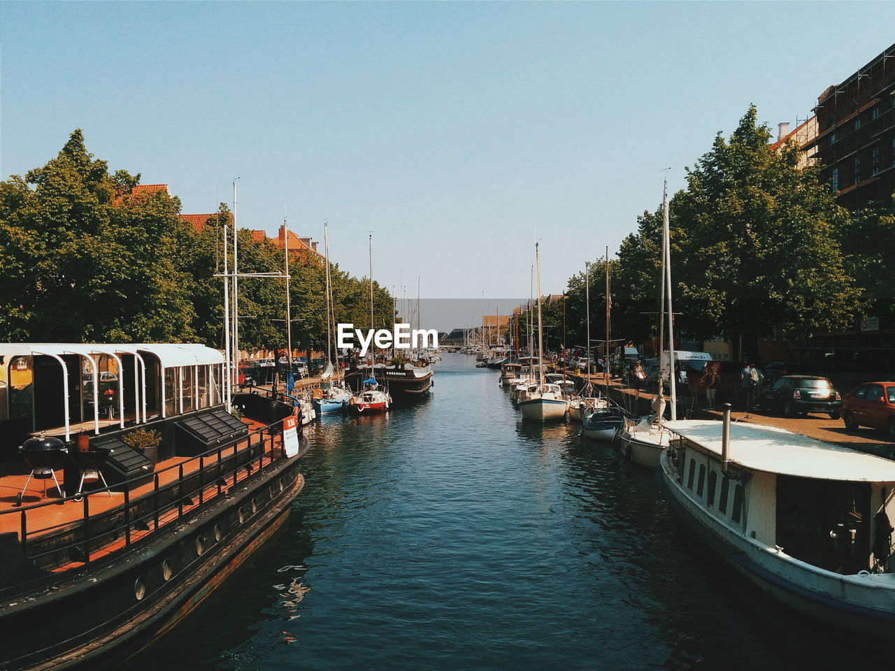 Boats at canal against clear sky in city