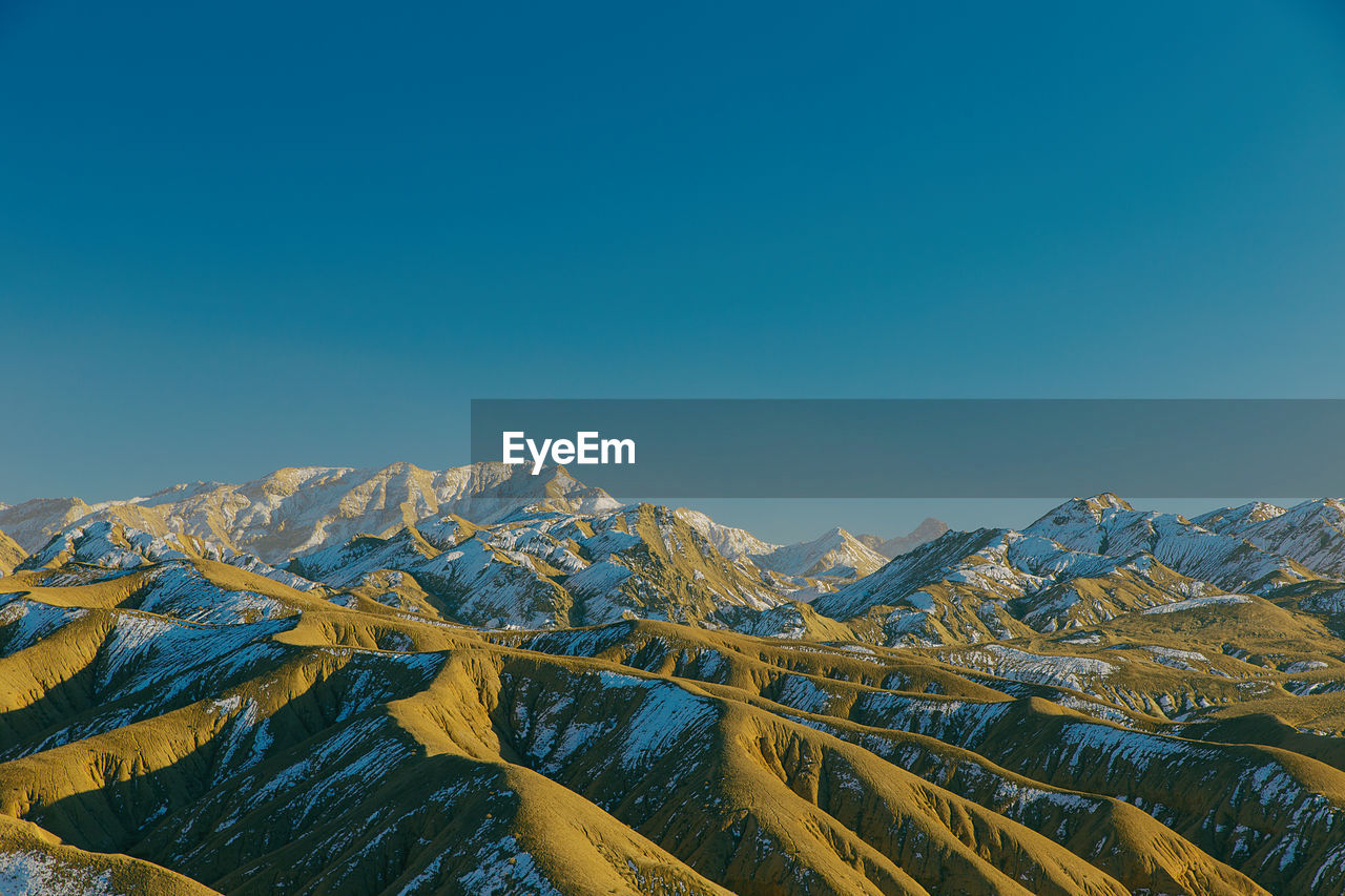 Scenic view of snowcapped mountains against clear blue sky