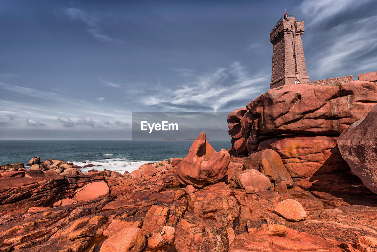 Men-ruz lighthouse in bretagne, france with scenic view of red cliffs agains blue sky