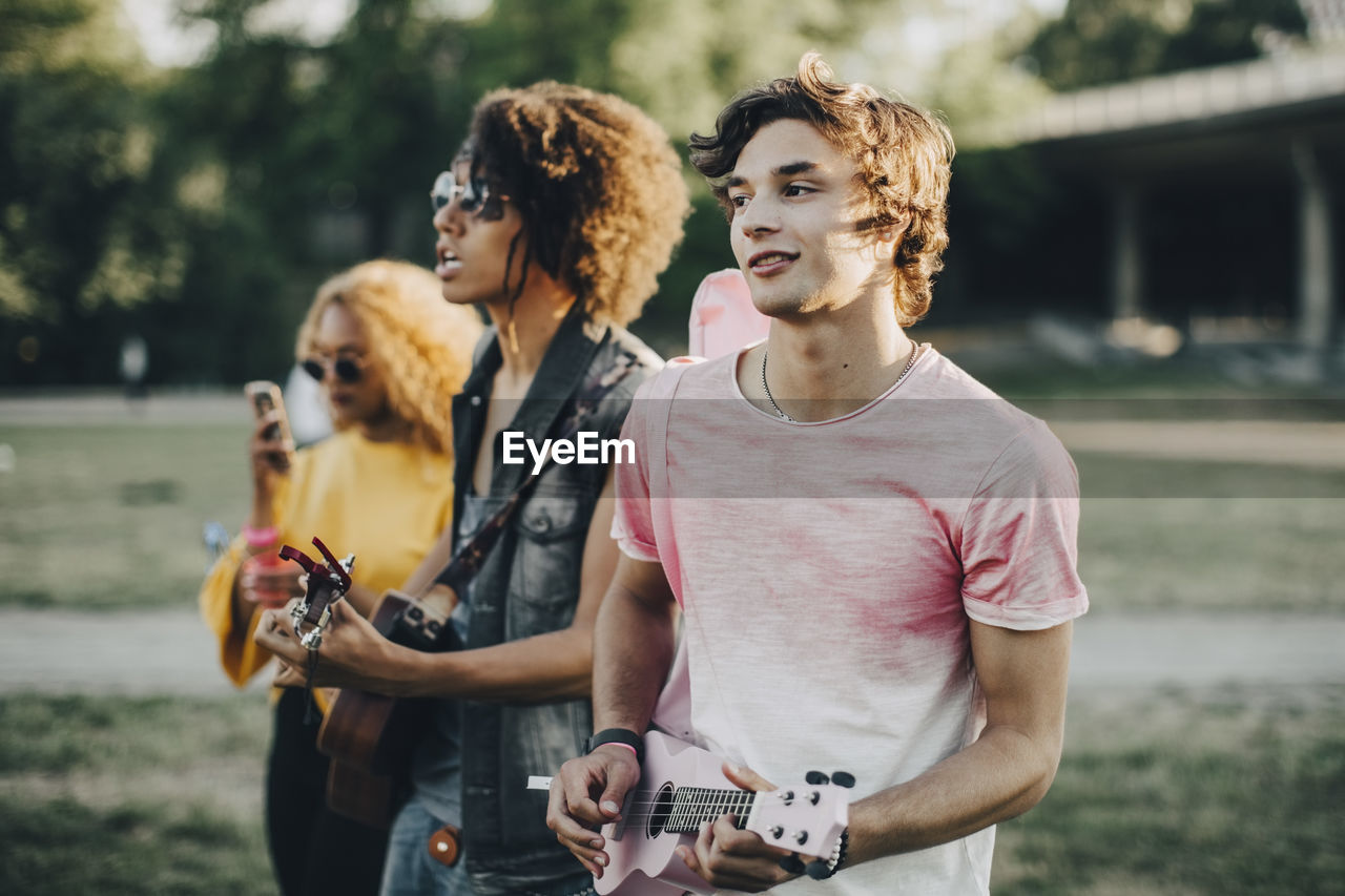 Young men playing ukulele while enjoying in music festival