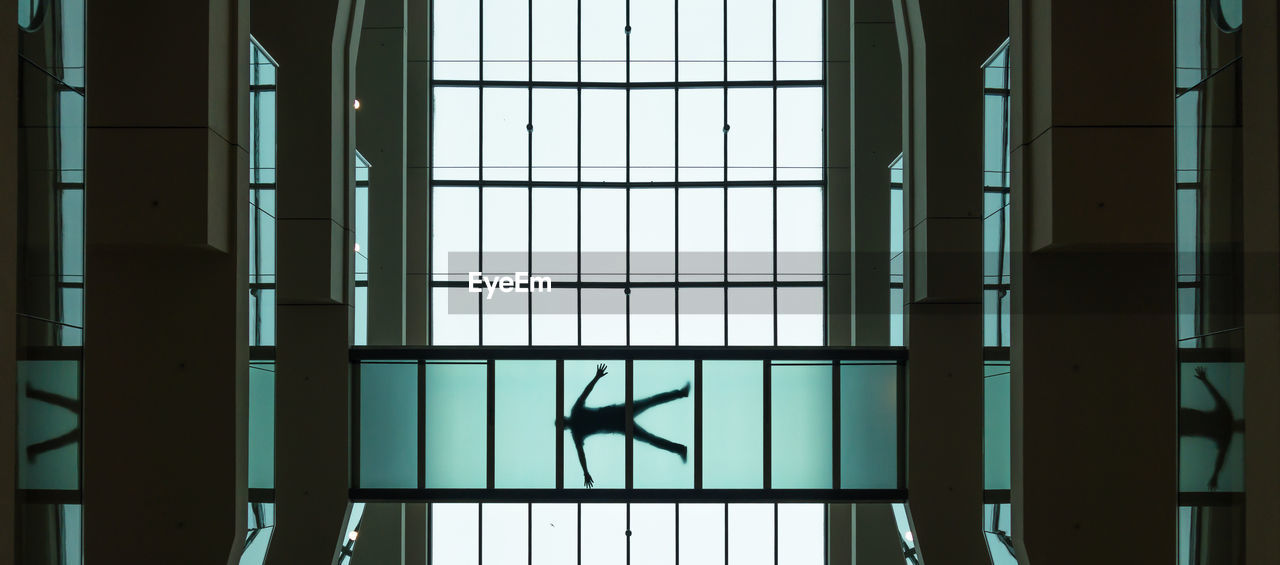 Low angle view of person lying on glass floor in building