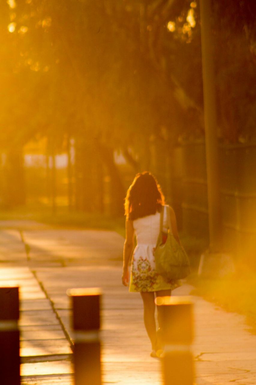 Rear view of woman walking on footpath