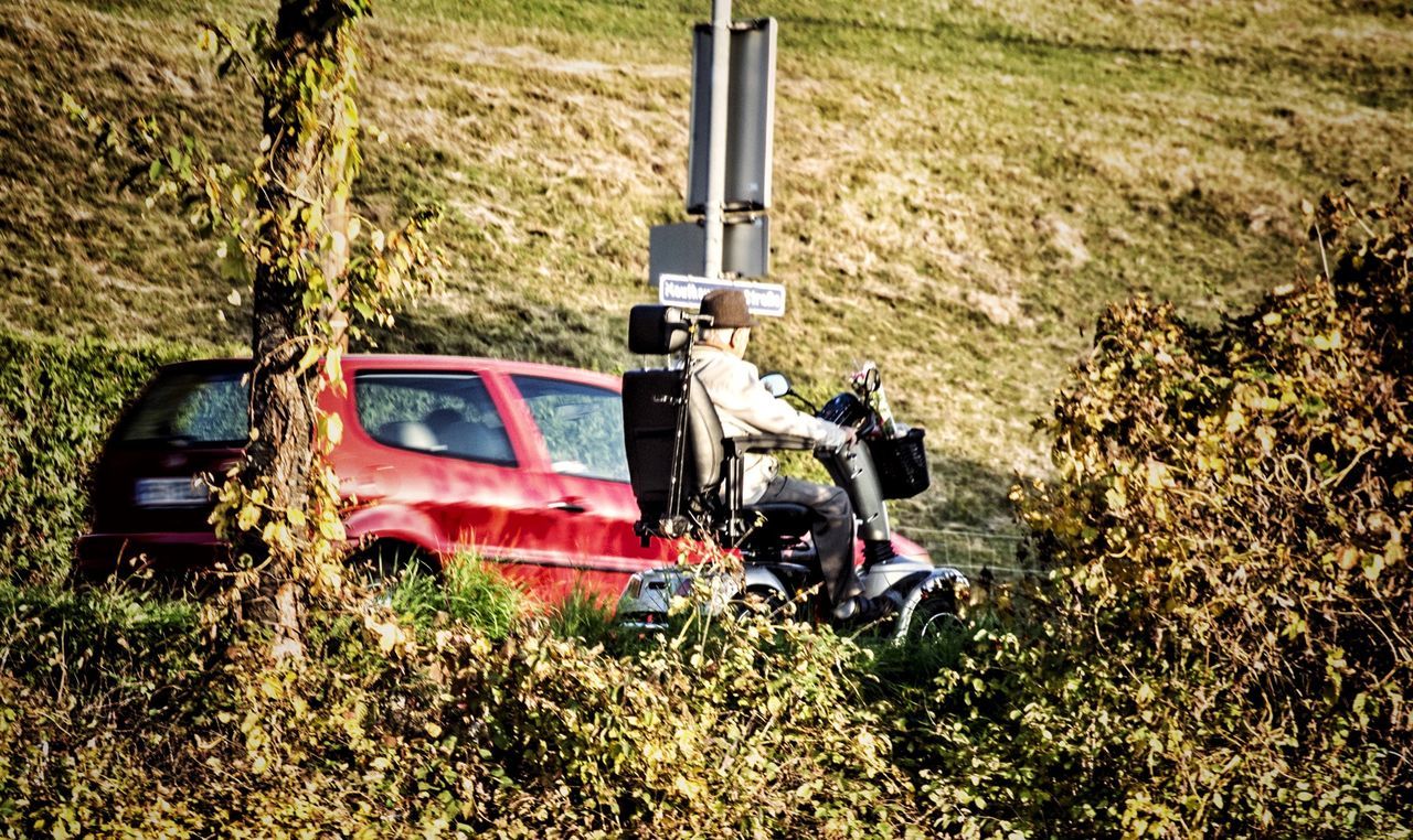 Side view of man riding motor scooter on country road