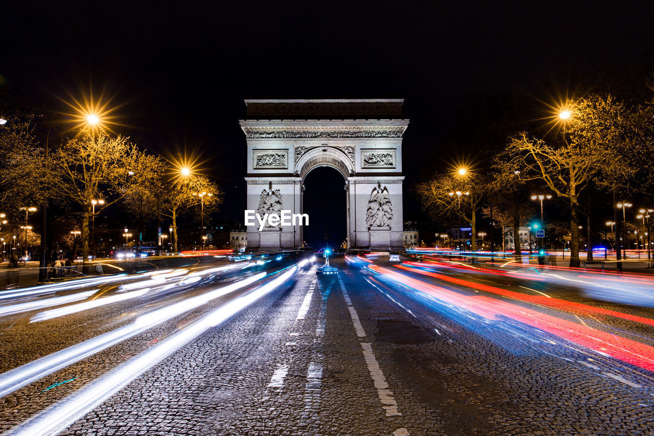 Light trails on street at arc de triomphe against sky