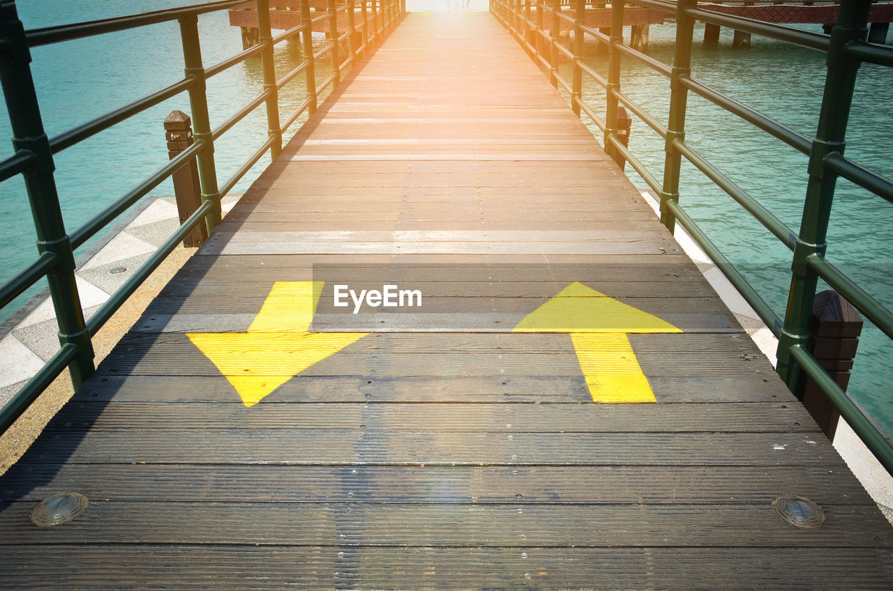 Two way yellow traffic arrows sign pointing to two direction on wooden bridge, making decisions. 